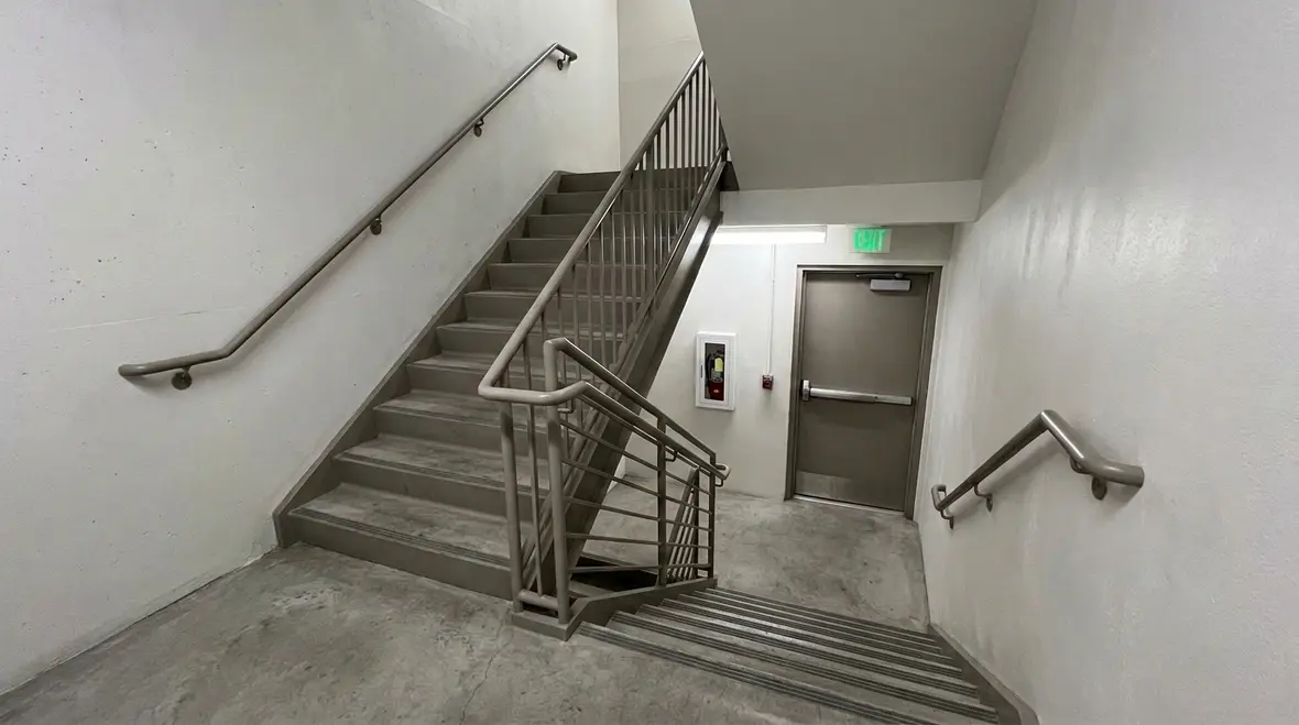 Interior staircase with handrails and a door at the bottom